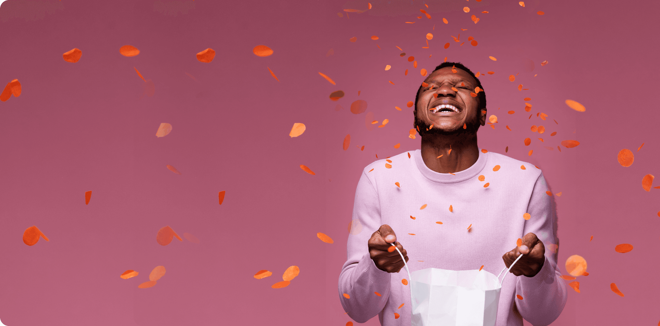 A man laughing mid-confetti as he opens an Unboxie gift bag
